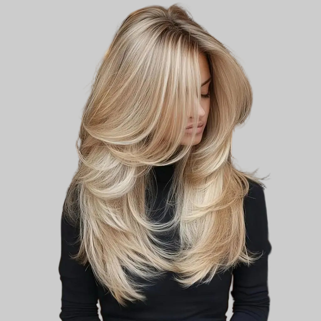 Woman with long, styled blonde hair in a blurred indoor setting