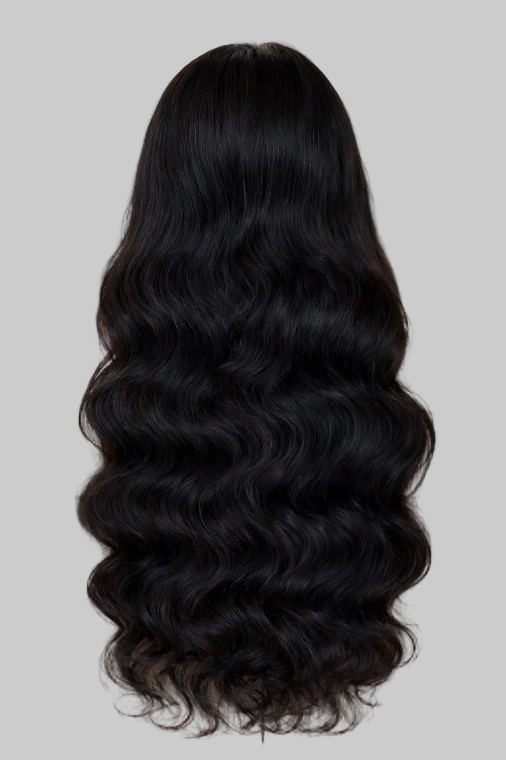 Person with long, black, wavy hair sitting in a chair.