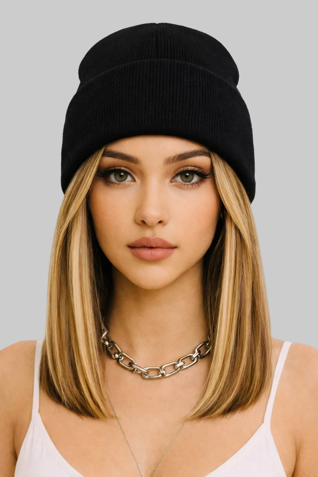 Woman wearing a black beanie and white top with a pink background